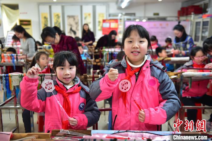 圖為小學(xué)生展示繡制好的2022年北京冬奧會吉祥物“冰墩墩”形象。　喻云亮 攝