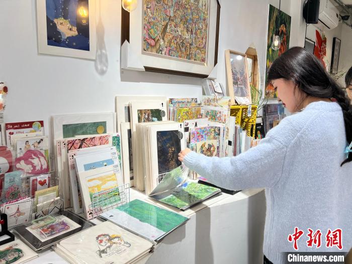 圖為藝術(shù)品商店內(nèi)，顧客挑選插畫作品?！＄婌?攝