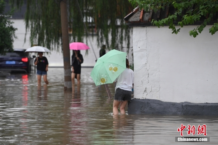 7月31日，市民行走在雨中的北京房山區(qū)瓦窯頭村。北京市氣象臺當(dāng)日10時(shí)發(fā)布分區(qū)域暴雨紅色預(yù)警信號。北京市水文總站發(fā)布洪水紅色預(yù)警，預(yù)計(jì)當(dāng)日12時(shí)至14時(shí)，房山區(qū)大石河流域?qū)⒊霈F(xiàn)紅色預(yù)警標(biāo)準(zhǔn)洪水。<a target='_blank' href='/'><p  align=