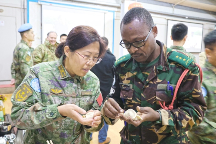 圖為維和官兵與外軍人員共同包餃子。胡光明攝