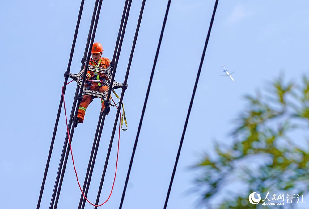 3月11日，在浙江省諸暨市河上鎮(zhèn)，浙江省送變電工程有限公司檢修人員在高空的導線上進行線路檢修維護。人民網(wǎng) 章勇濤攝