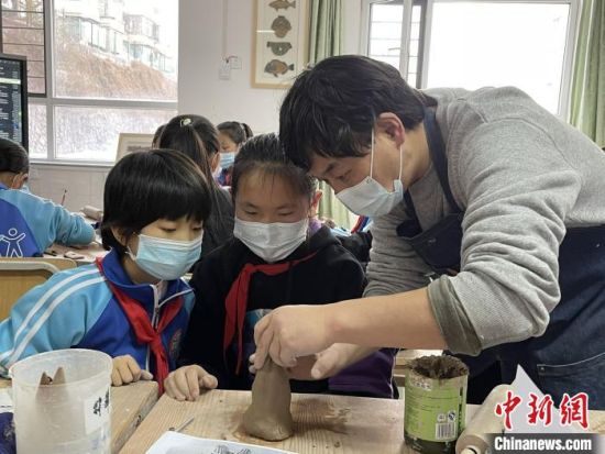 圖為西寧市勞動路小學教師賈煜與學生一起制作陶藝?！≈苋鸪阶?攝