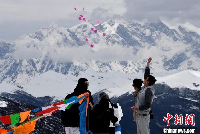 圖為5月14日，游客在西藏林芝色季拉山觀景臺拋灑“隆達(dá)”(風(fēng)馬旗，藏族民眾的一種祈福方式)?！±盍?攝