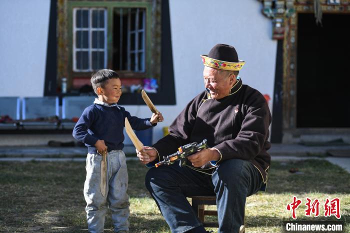 圖為米林縣扎西繞登鄉(xiāng)彩門村64歲的洛桑帶著孫子巴桑在院子的草地上玩耍?！『闻罾?攝