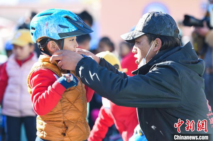 圖為拉薩市實(shí)驗(yàn)幼兒園孩子在教練的幫助下穿戴頭盔?！『闻罾?攝