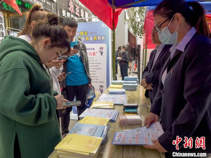 圖為工作人員正在向路過(guò)市民介紹國(guó)家反詐中心軟件的功能。　謝牧 攝