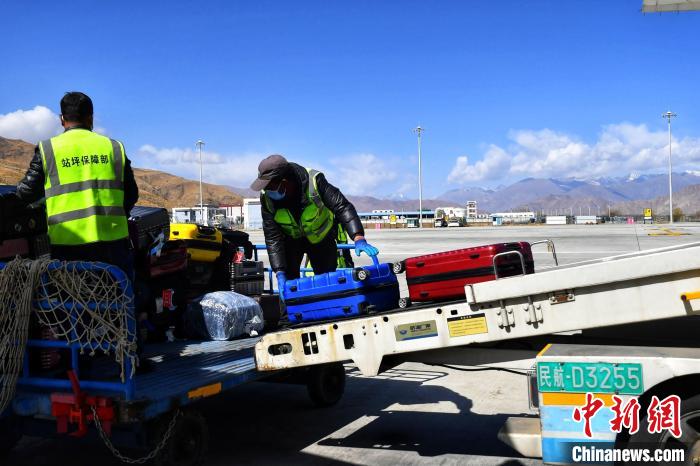 圖為機(jī)場工作人員傳送旅客行李箱?！≈芎?攝